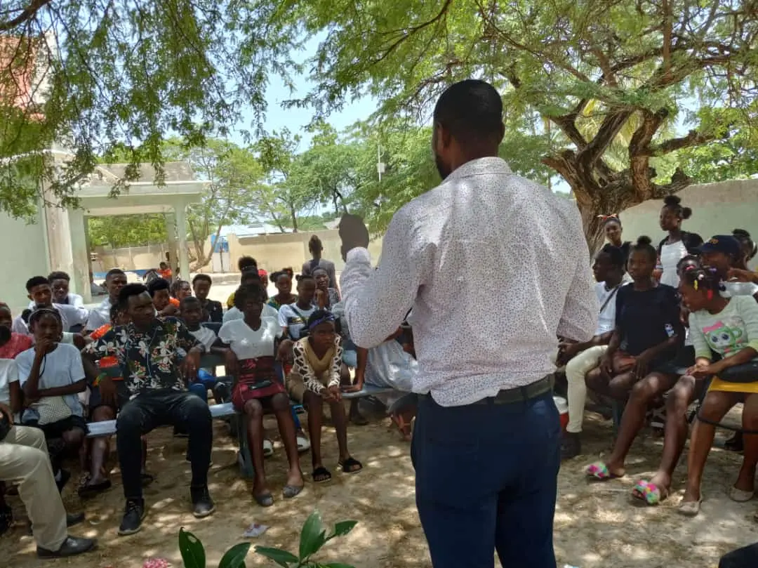 Un intervenant échange avec des membres de la communauté réunis en plein air
